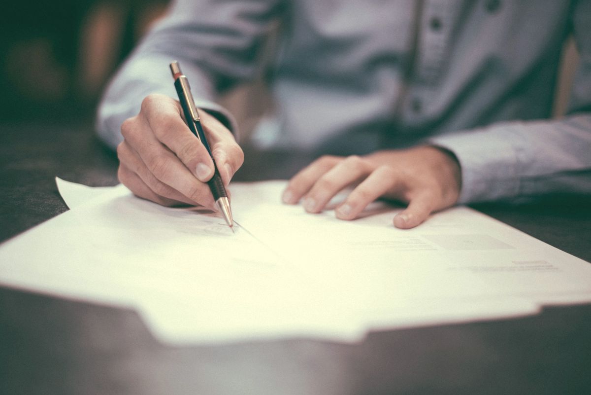Hand signing a printed document with a pen